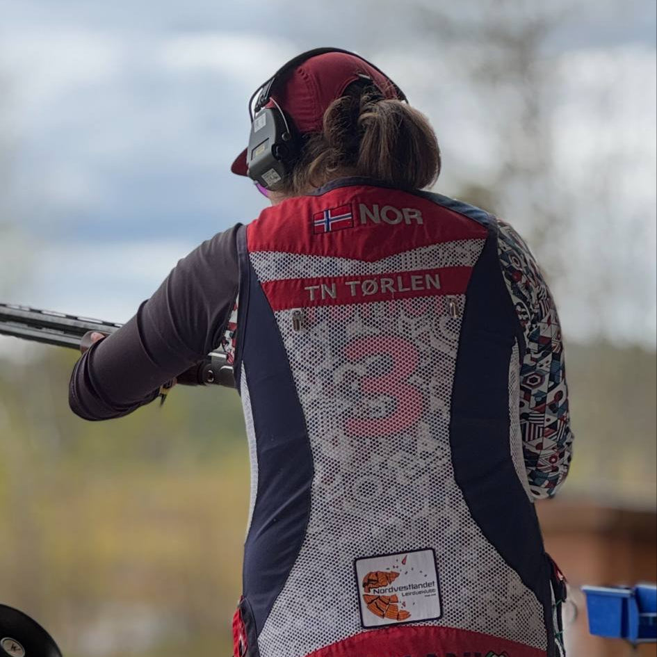 TrapCrackshots Competition Jersey – form-fitting clay shooting shirt for women. Tested for one season, worn by Therese in size L. Designed for focus, performance, and competition attitude. Colorful and fun.